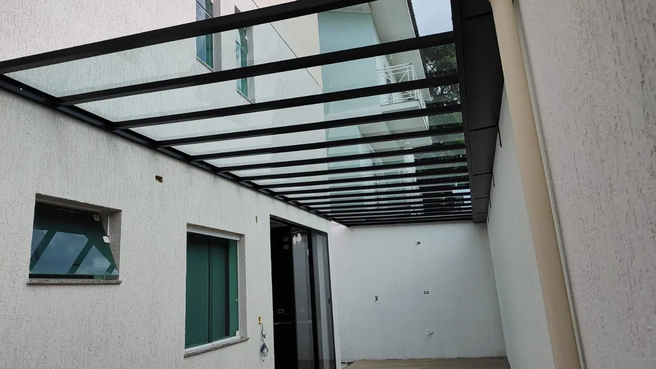 Cobertura fixa transparente com estrutura preta em quintal em São Paulo