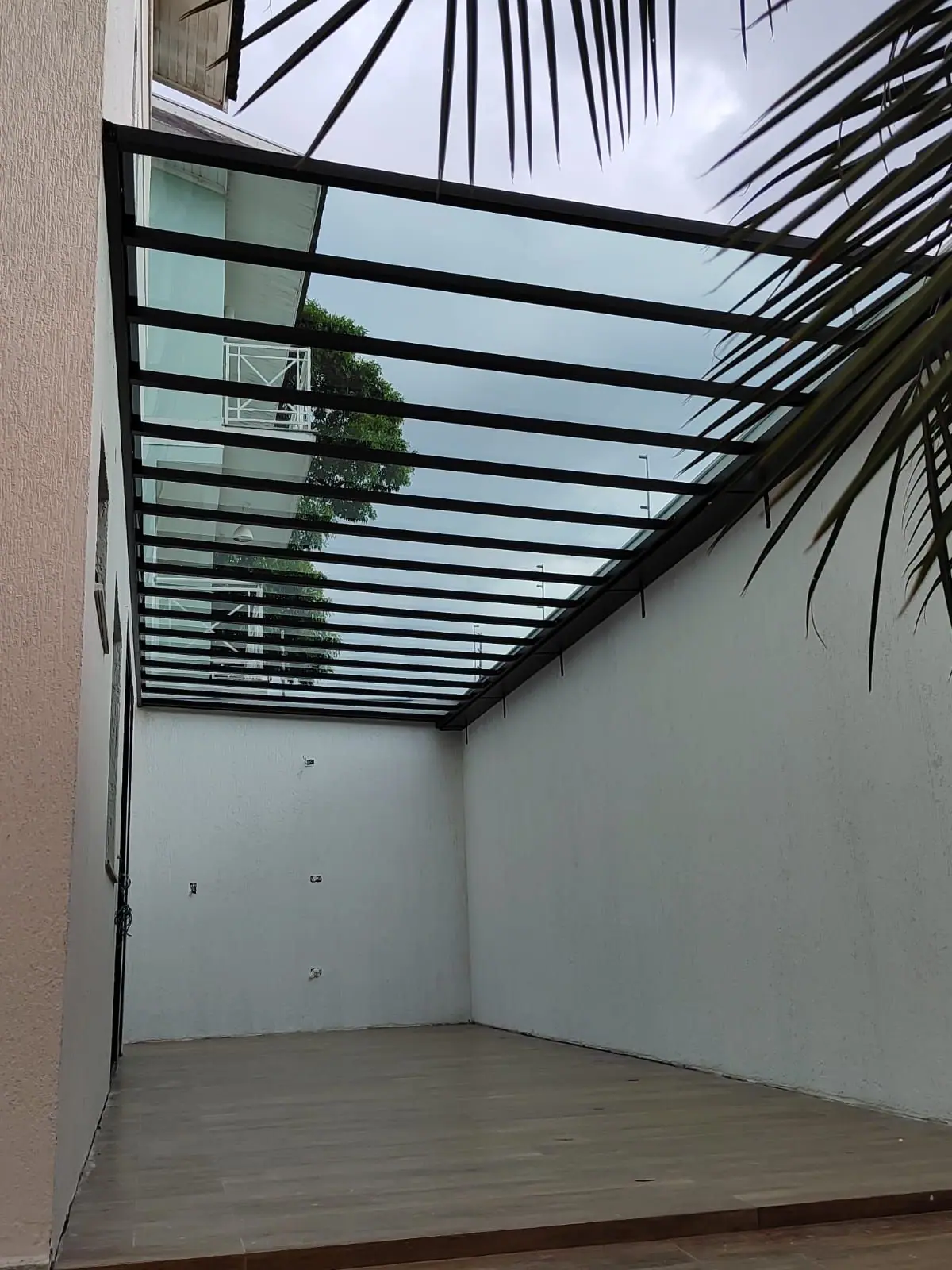 Cobertura fixa transparente com estrutura preta em área externa em São Paulo