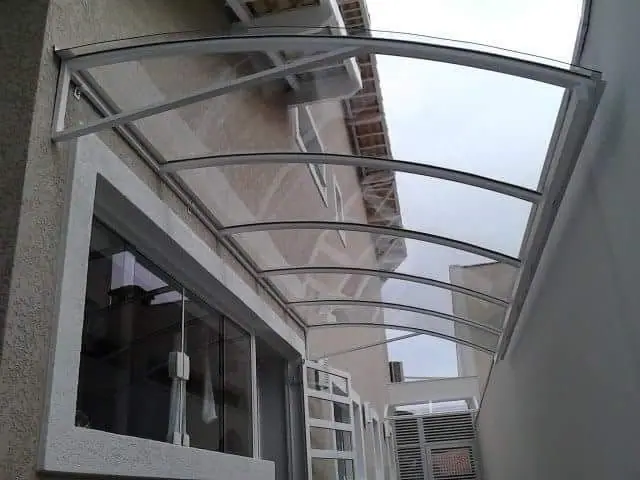 Toldo de policarbonato em arco sobre janela de sala em São Paulo