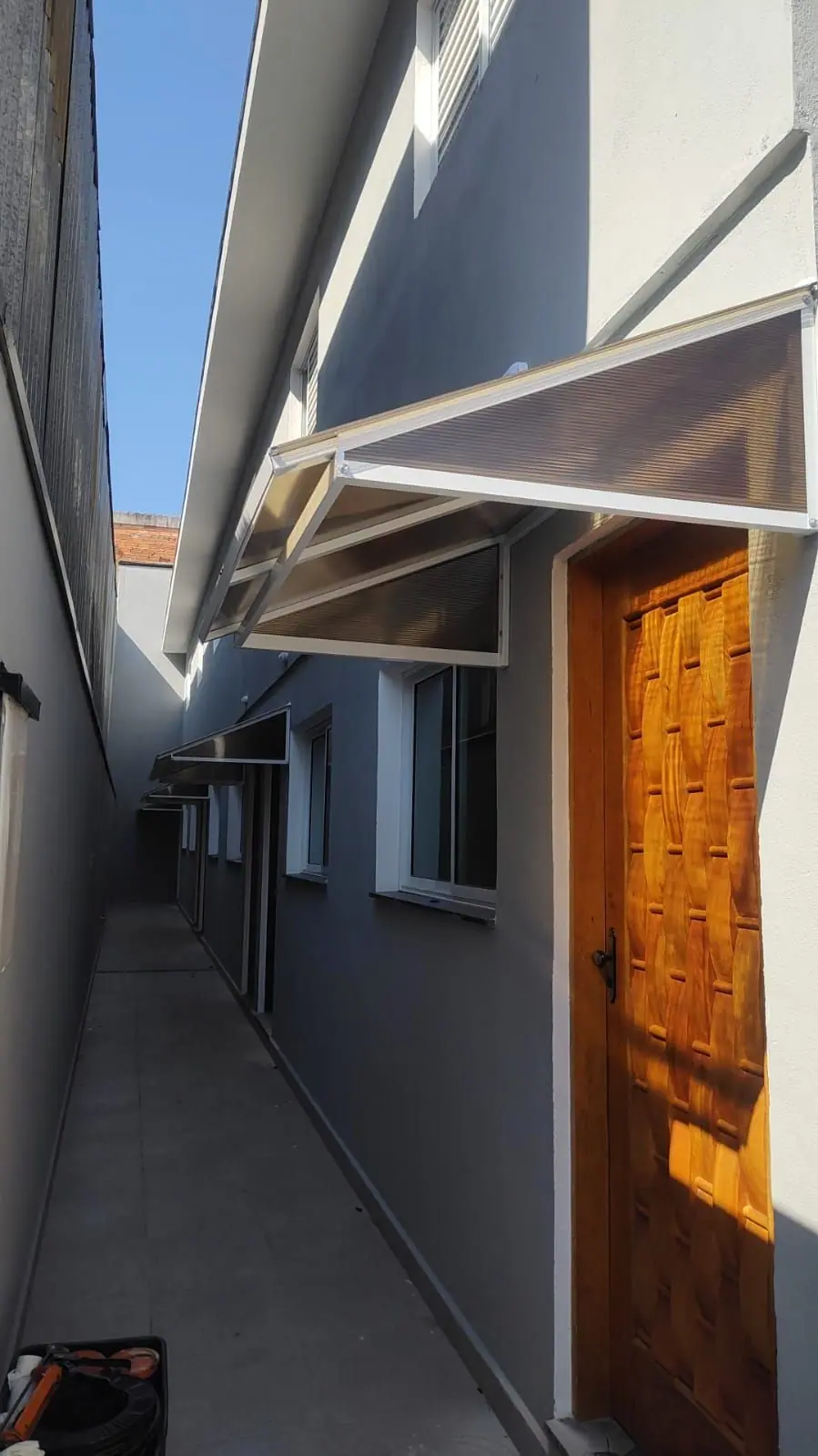 Toldo de policarbonato sobre porta de casa em São Paulo
